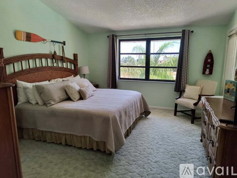 A bedroom with a large bed and a window overlooking a green area.