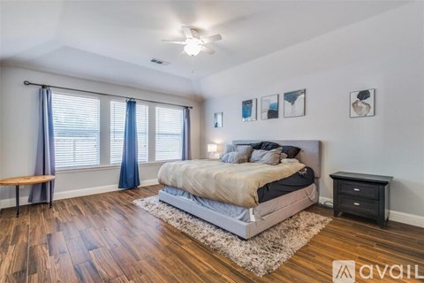 A bedroom with a bed, nightstand, and a window with blue curtains.