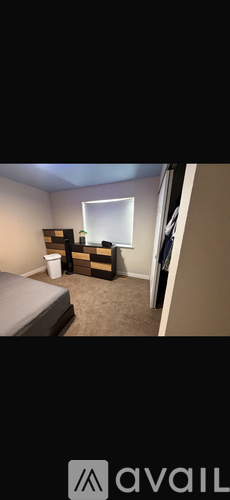 A room with a bed, a window, and a small table with a bottle on it.