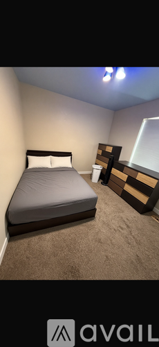 A bedroom with a bed, nightstand, and a window.