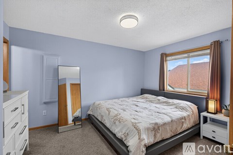 A bedroom with a bed, dresser, and mirror.