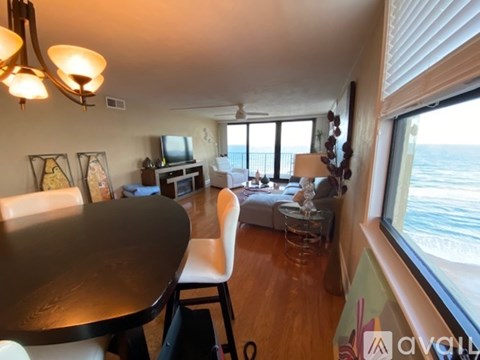 A living room with a table and chairs and a view of the ocean.