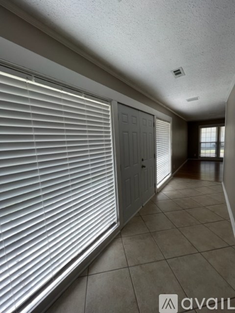 A hallway with a closed door and a window with blinds.