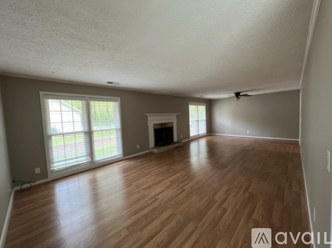 A spacious room with wooden floors and a fireplace.