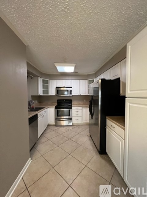 A kitchen with a black refrigerator and white cabinets.