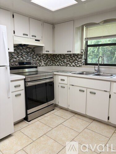 A kitchen with white cabinets and a black and white backsplash.