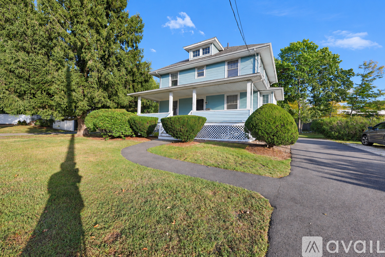 A house with a blue exterior and a white fence is surrounded by greenery.