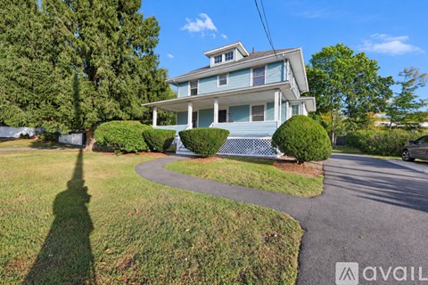 A house with a blue exterior and a white fence is surrounded by greenery.
