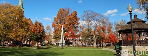 A park with a gazebo and trees with autumn leaves.