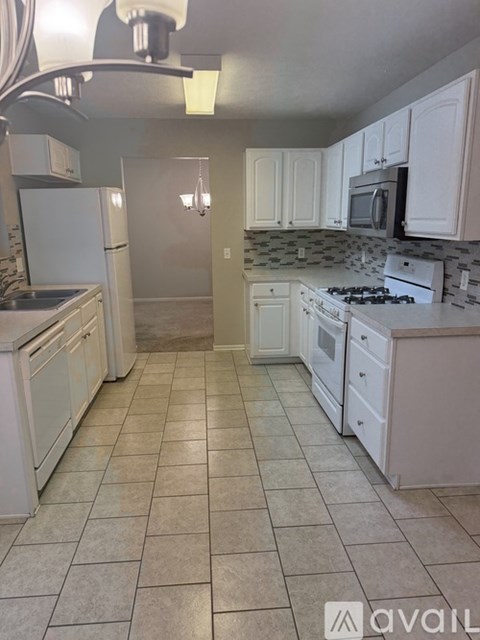 A kitchen with white appliances and a tiled floor.