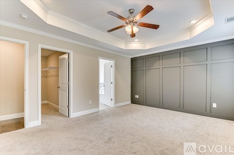 A spacious room with a ceiling fan and carpeted floor.