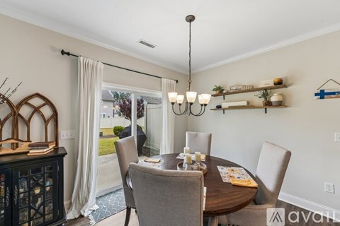 A dining room with a table set for two and a chandelier hanging from the ceiling.