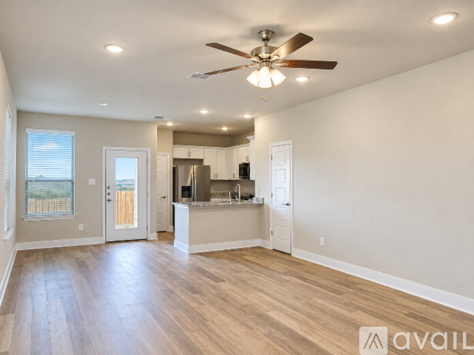 A spacious living room with a ceiling fan and hardwood floors.
