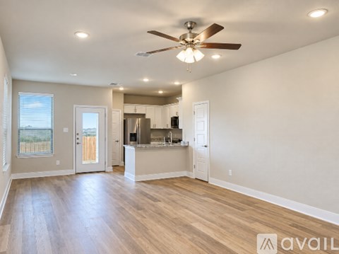 A spacious living room with a ceiling fan and hardwood floors.