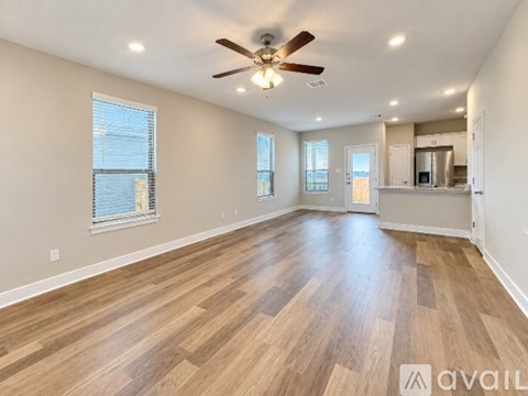 A spacious room with wooden flooring and a ceiling fan.