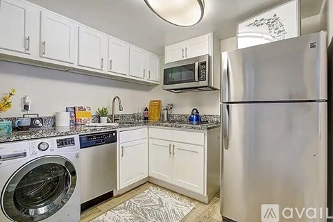 A kitchen with a washing machine, microwave, and refrigerator.