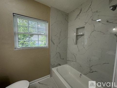 A bathroom with a marble wall and a window with blinds.