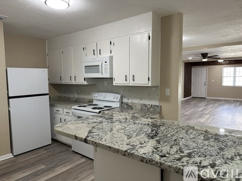 A kitchen with white cabinets and a marble countertop.