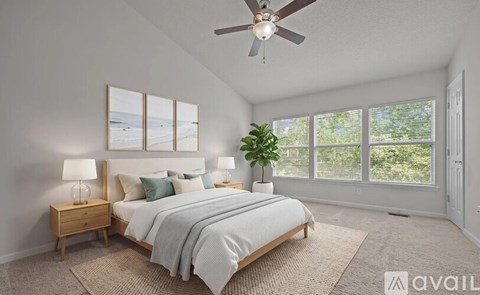 A bedroom with a large bed, a ceiling fan, and a view of the outdoors through the windows.