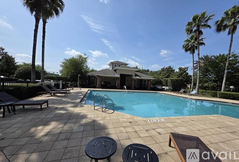 A pool surrounded by palm trees and a house in the background.
