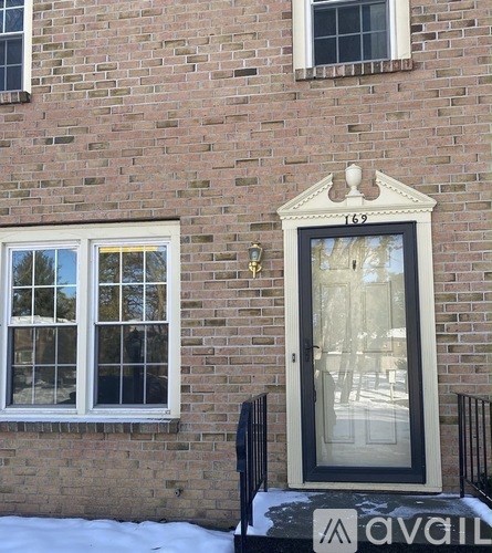 A brick building with a black door and a window with a view of trees.