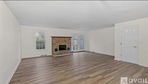 A spacious room with a fireplace and wooden flooring.