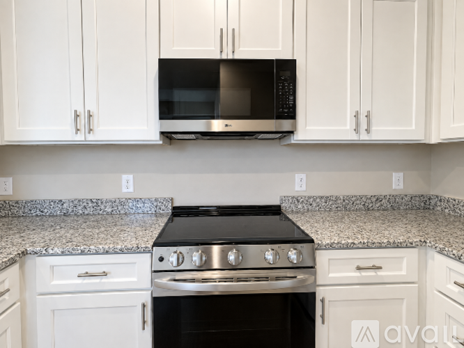 A kitchen with white cabinets and a black stove top oven.