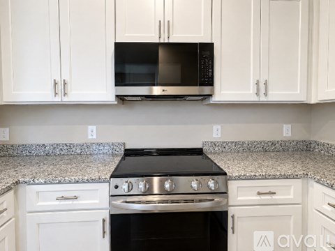 A kitchen with white cabinets and a black stove top oven.