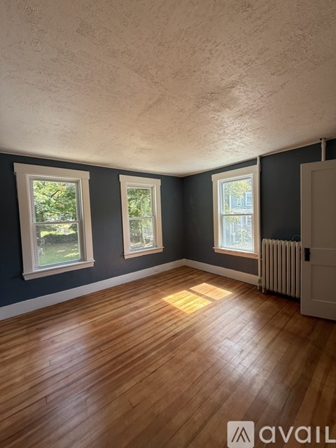 A room with wooden floors and three windows.