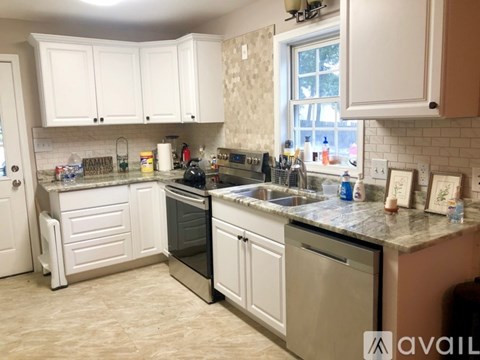 A kitchen with white cabinets and a marble countertop.