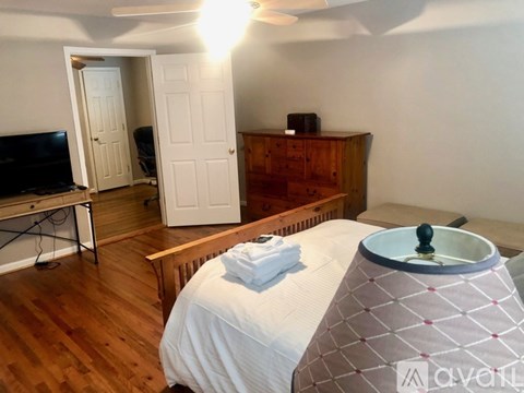 A bedroom with a bed, a dresser, and a television.