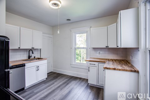 A kitchen with white cabinets and a wooden countertop.