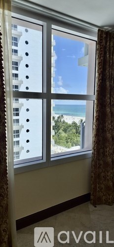 A window with a view of a beach and a building.