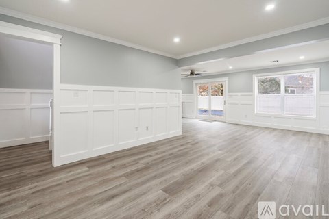 A spacious room with wooden flooring and white walls.