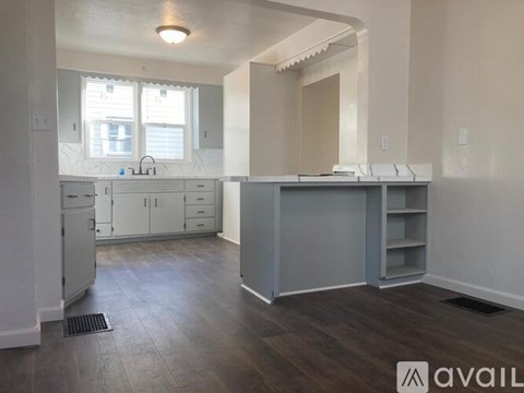 A kitchen with white cabinets and a grey island.