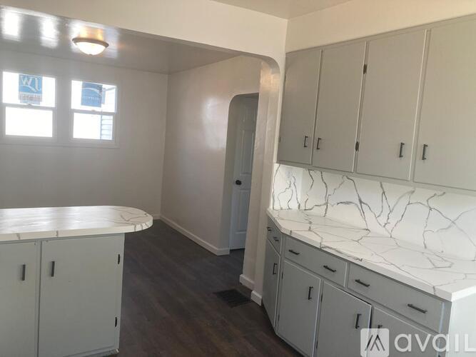 A kitchen with white cabinets and a marble countertop.