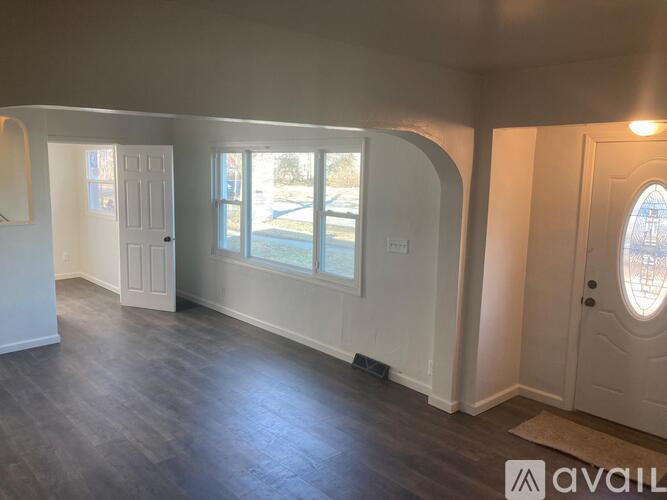 A room with white walls and a wooden floor with a door on the right side.