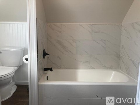 A white toilet is next to a bathtub in a bathroom.
