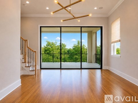 A spacious room with wooden floors and a large glass door leading to a balcony.