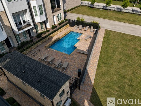 A swimming pool surrounded by a stone wall and lounge chairs.