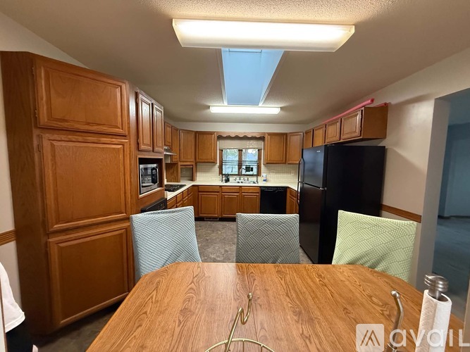 A kitchen with wooden cabinets and a table in the foreground.
