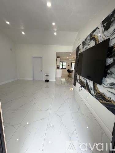 A spacious room with a marble floor and a television mounted on the wall.