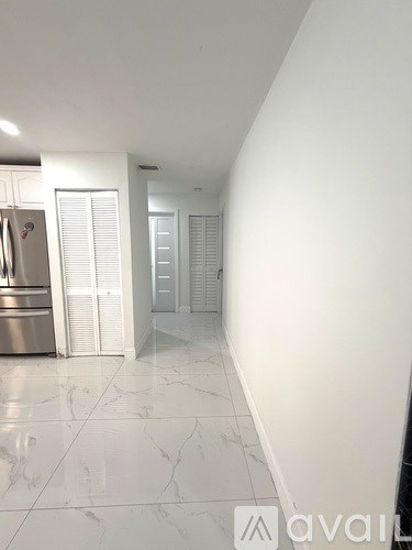 A kitchen with a refrigerator and a white tiled floor.