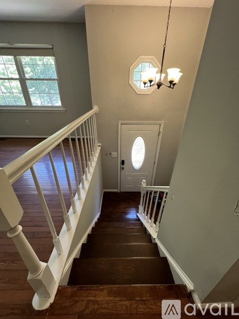 A staircase with a white railing and wooden steps leading to a door with a round window above it.