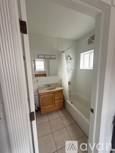 A small bathroom with a sink, mirror, and bathtub.