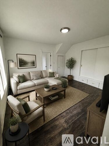 A living room with a white sofa, a wooden coffee table, and a painting on the wall.