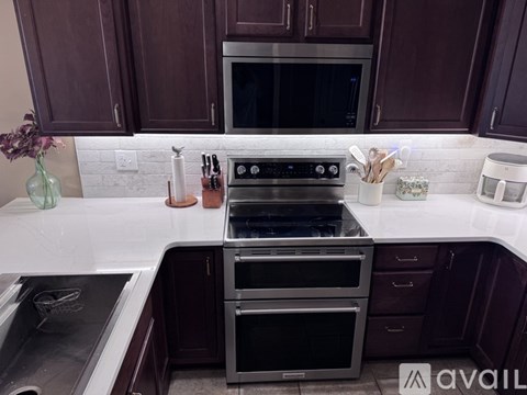A kitchen with dark brown cabinets and a white countertop with a stove and oven.