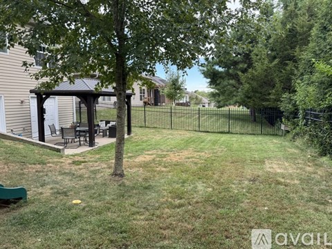 A backyard with a tree, a gazebo, and a fence.