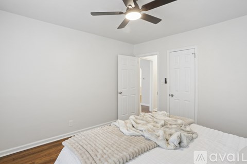 A bedroom with a bed covered in a white blanket and a ceiling fan.