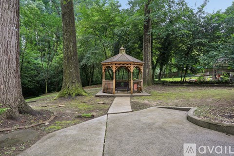 A gazebo is situated in the middle of a tree-filled park.